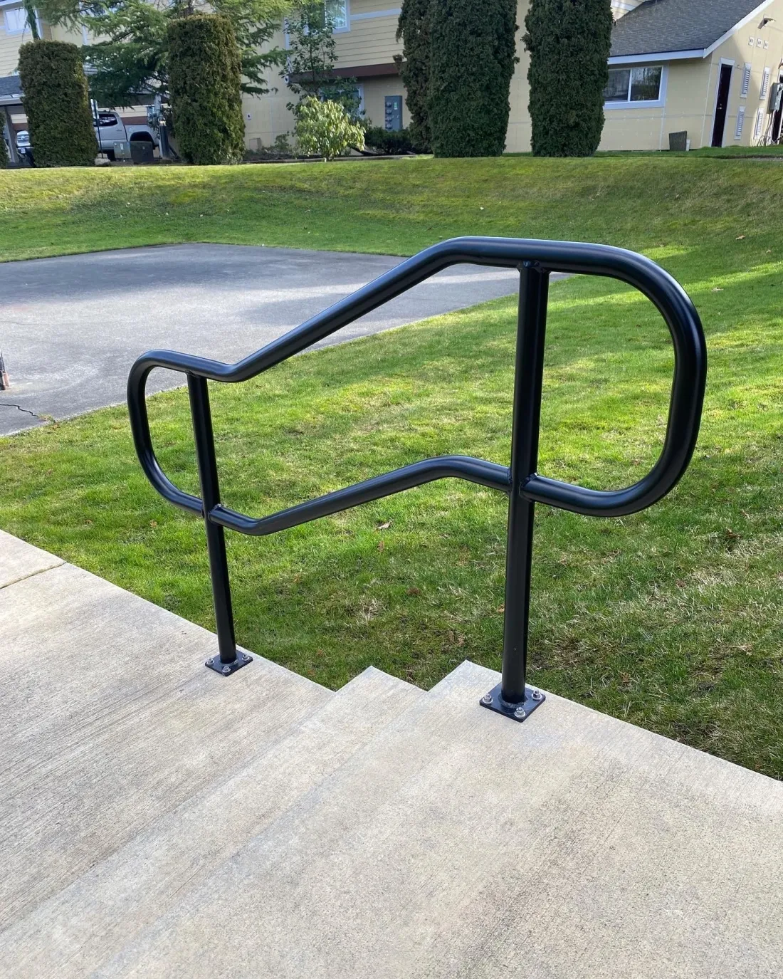Black steel handrail along an exterior concrete walkway and stairs